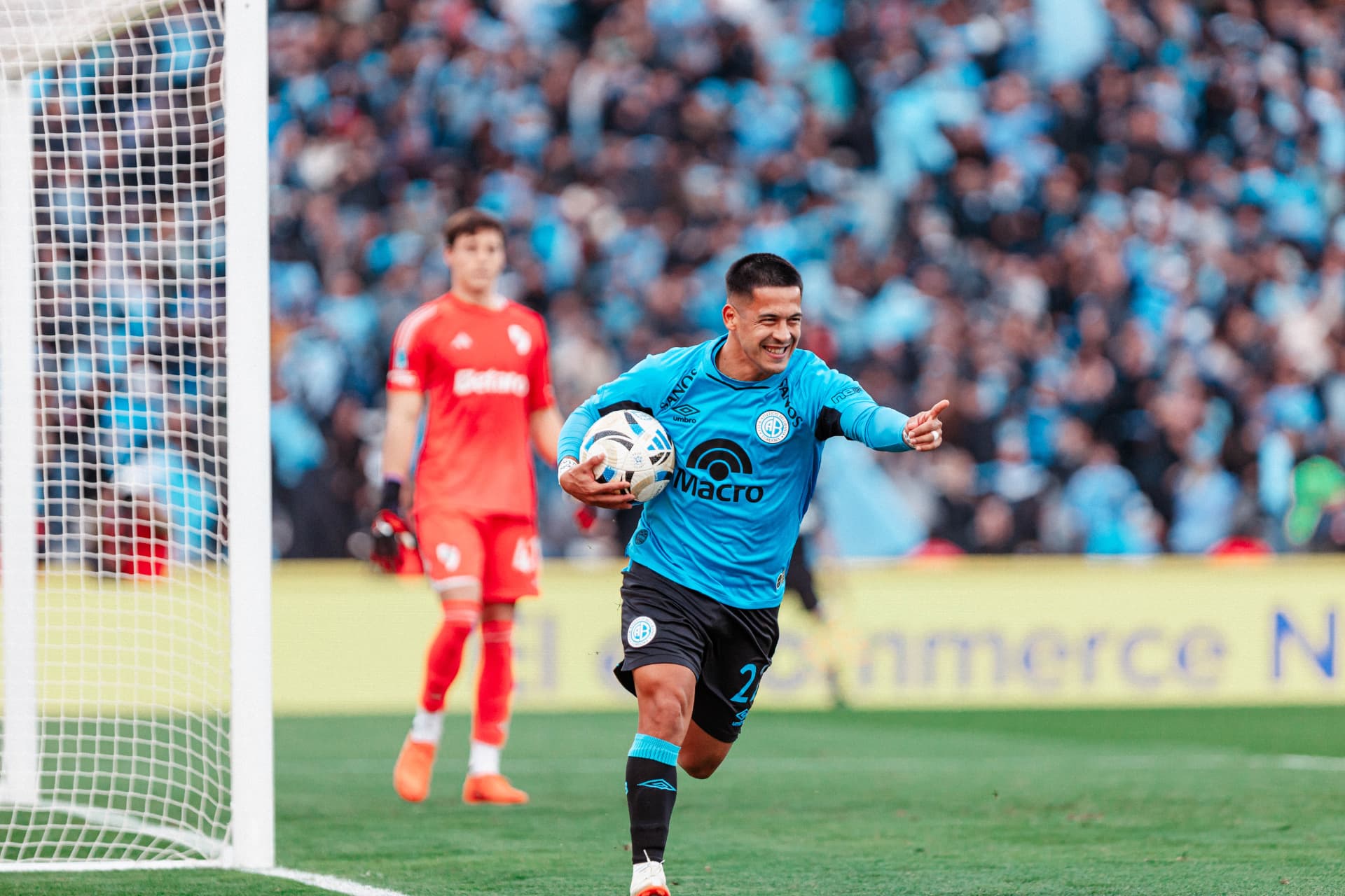 Jugador de Belgrano festejando un gol con la pelota en la mano junto al arco