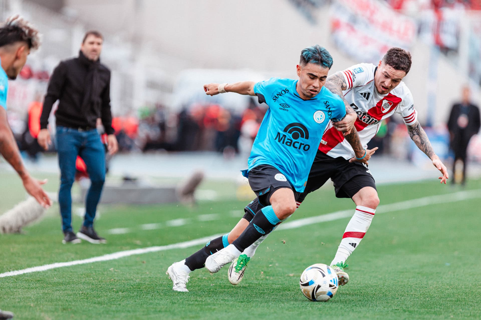 Jugador de Belgrano protegiendo la pelota ante la marca de un rival