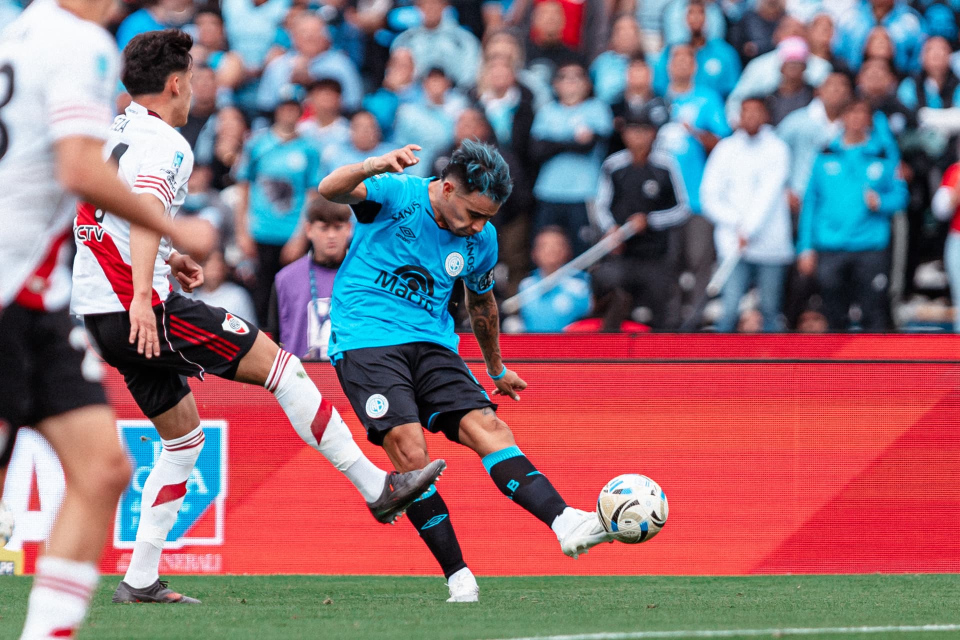 Remate de un jugador de Belgrano con la tribuna celeste de fondo