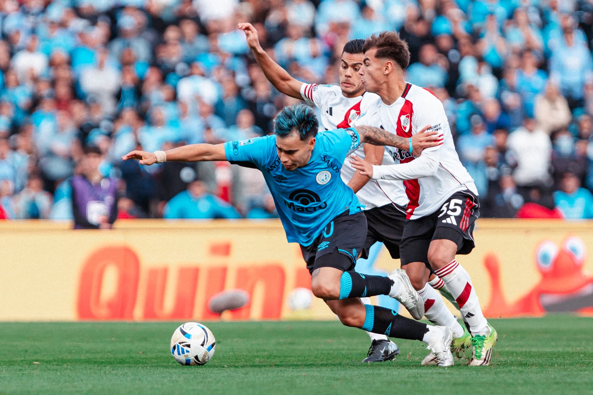Volante de Belgrano quebrando la marca de dos rivales en el mediocampo