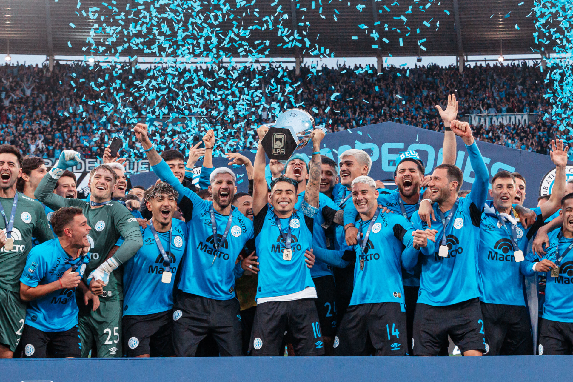 Plantel de Belgrano levantando el trofeo entre papelitos en el estadio